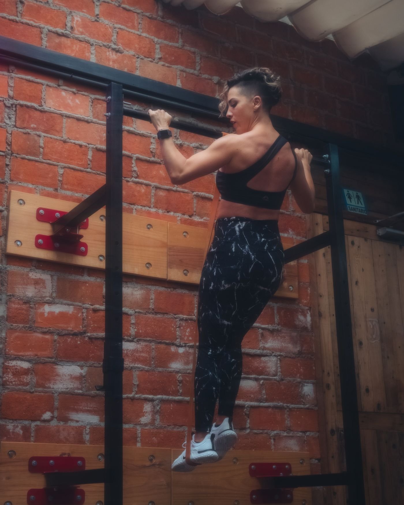 Woman performing a strict pull-up on an indoor gym bar