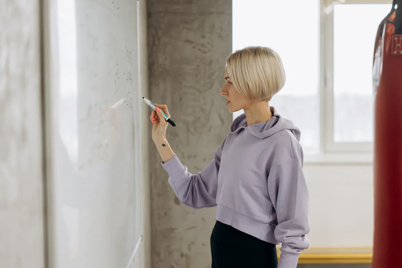Woman writing a workout plan on a gym whiteboard