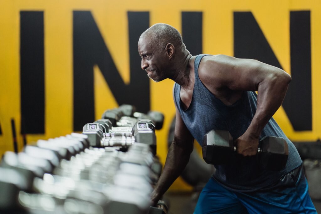 Older man performing a dumbbell exercise in a gym