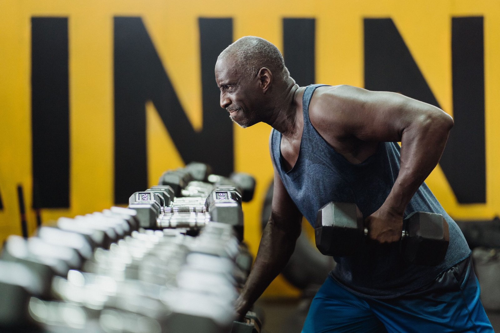 Older man performing a dumbbell exercise in a gym