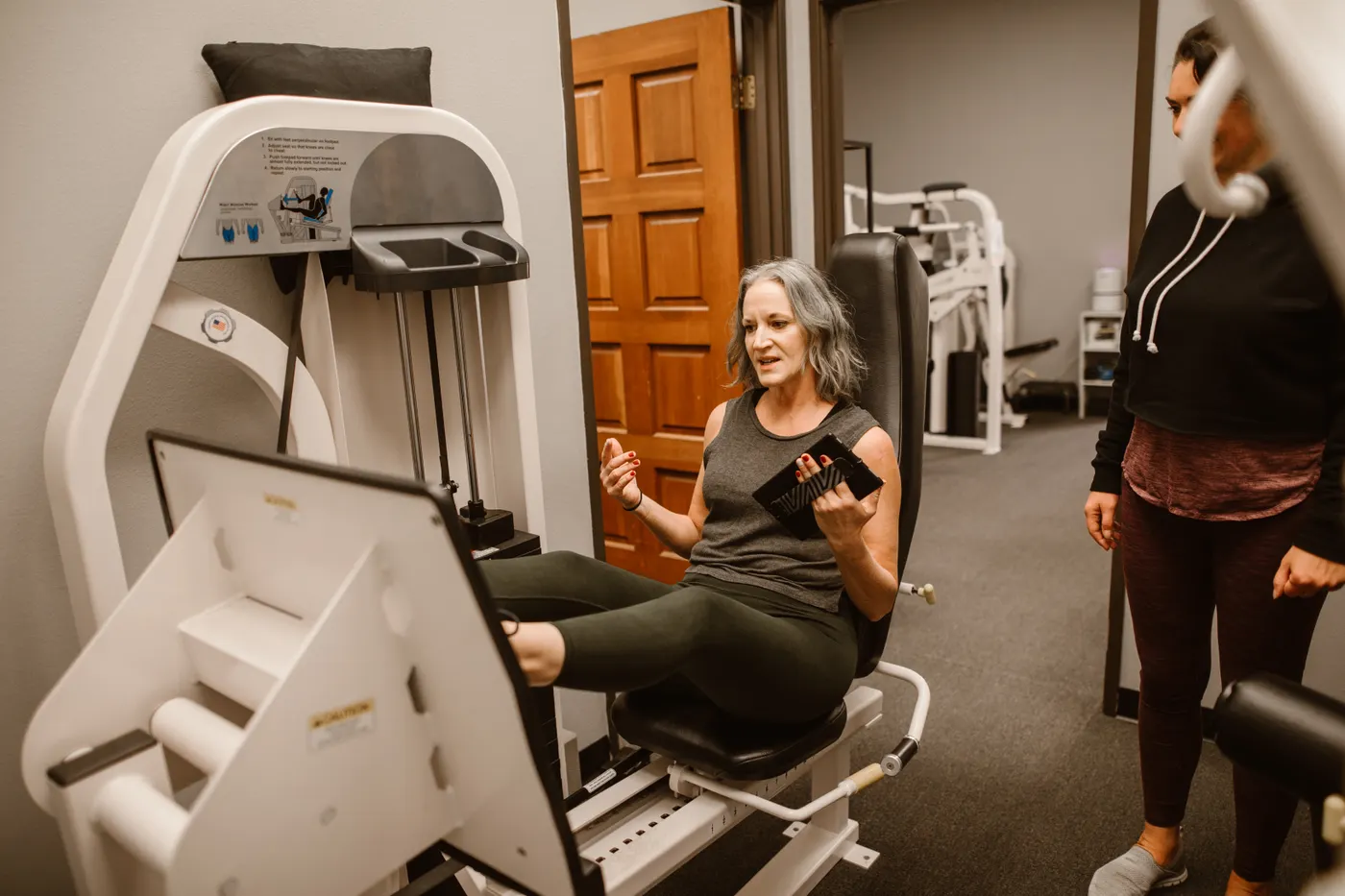 Older woman performing supervised leg press exercise with a trainer