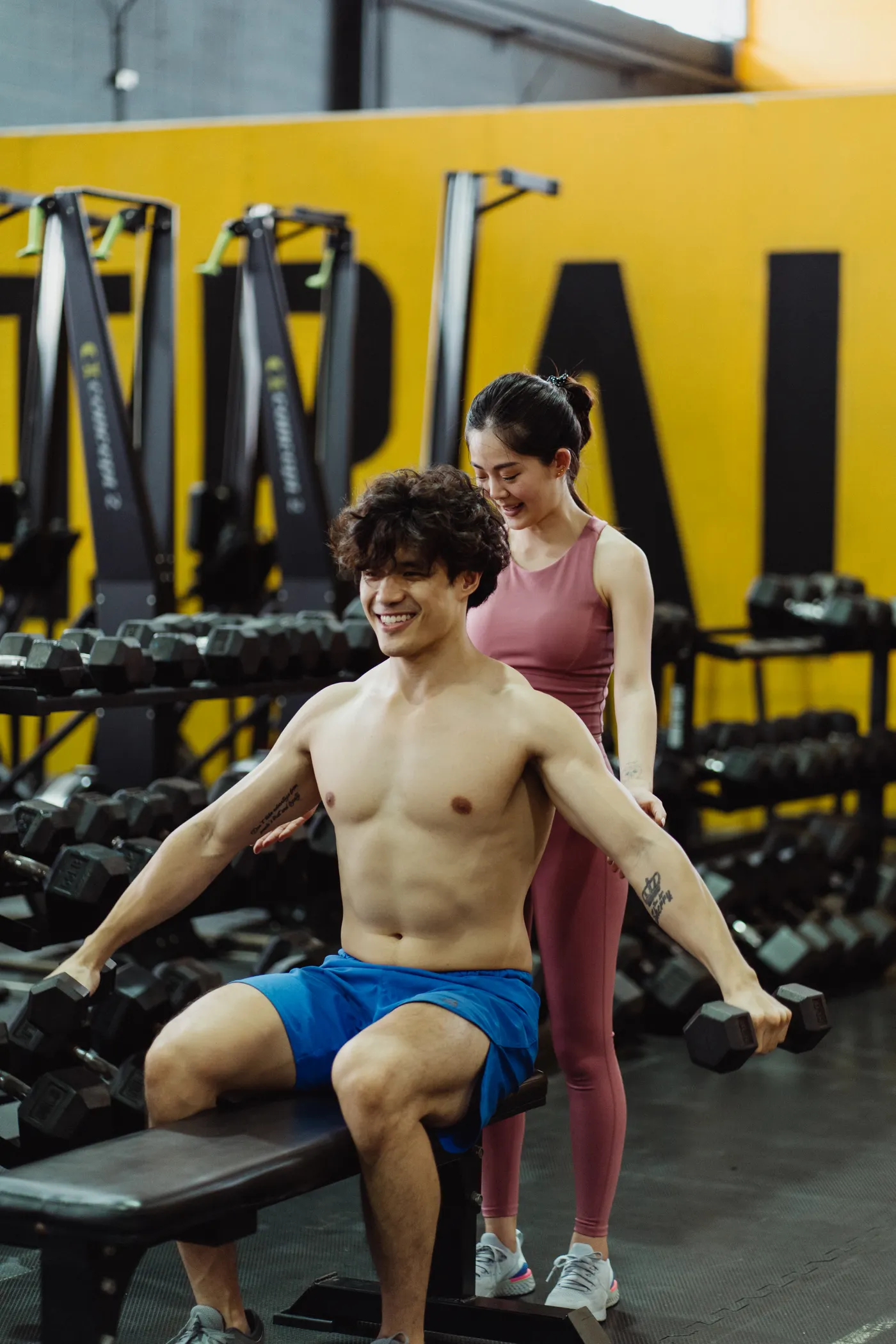 Trainer guiding a man through a dumbbell strength exercise