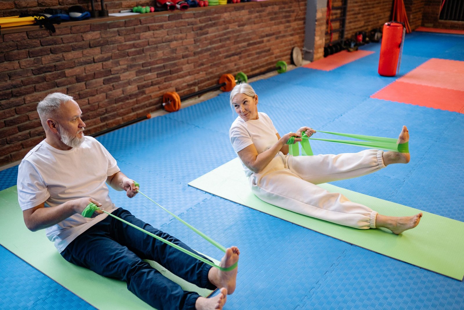 Older couple exercising with resistance bands on mats