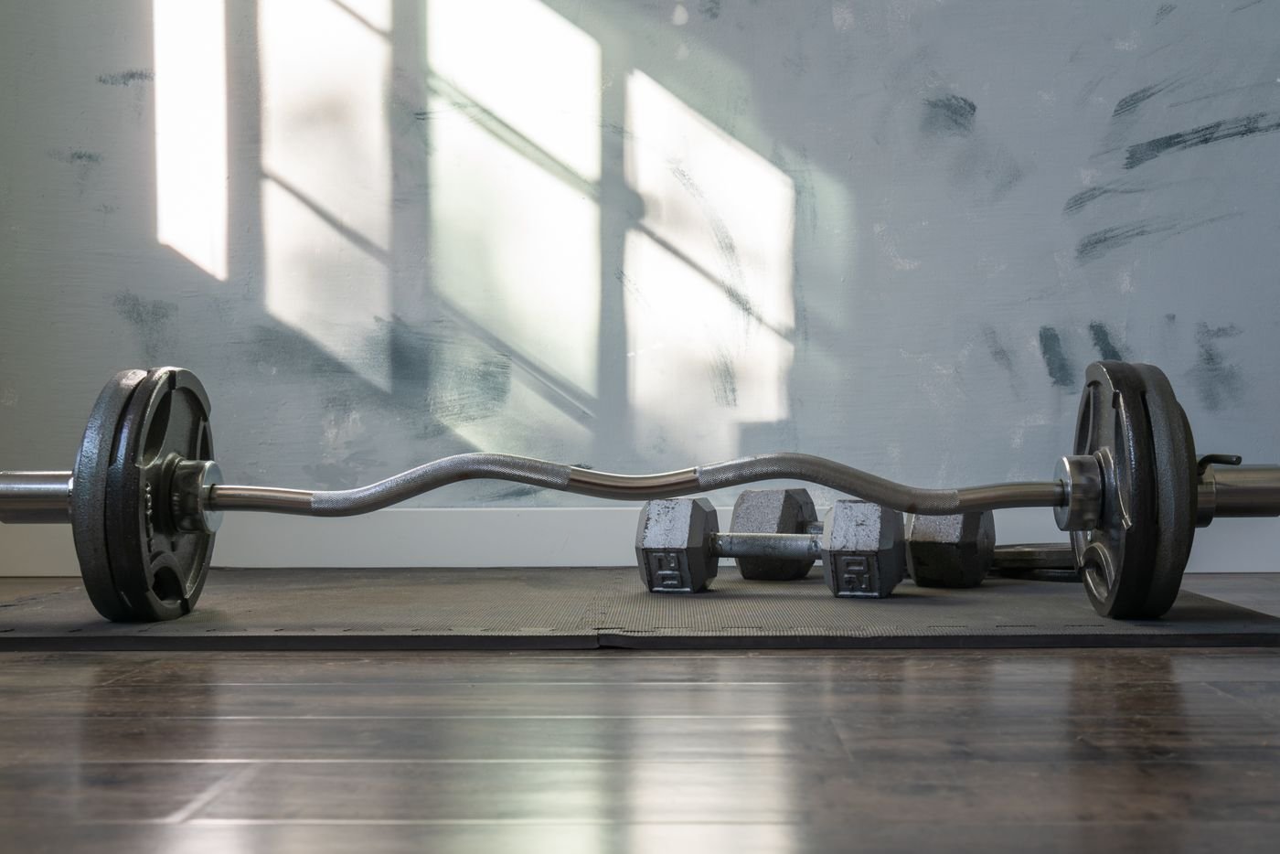 Dumbbells and barbell laid out on a training floor