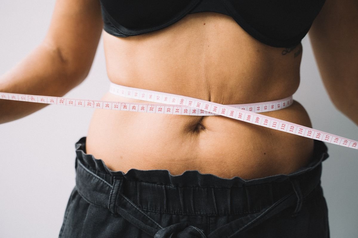 Person measuring their waist with a tape measure