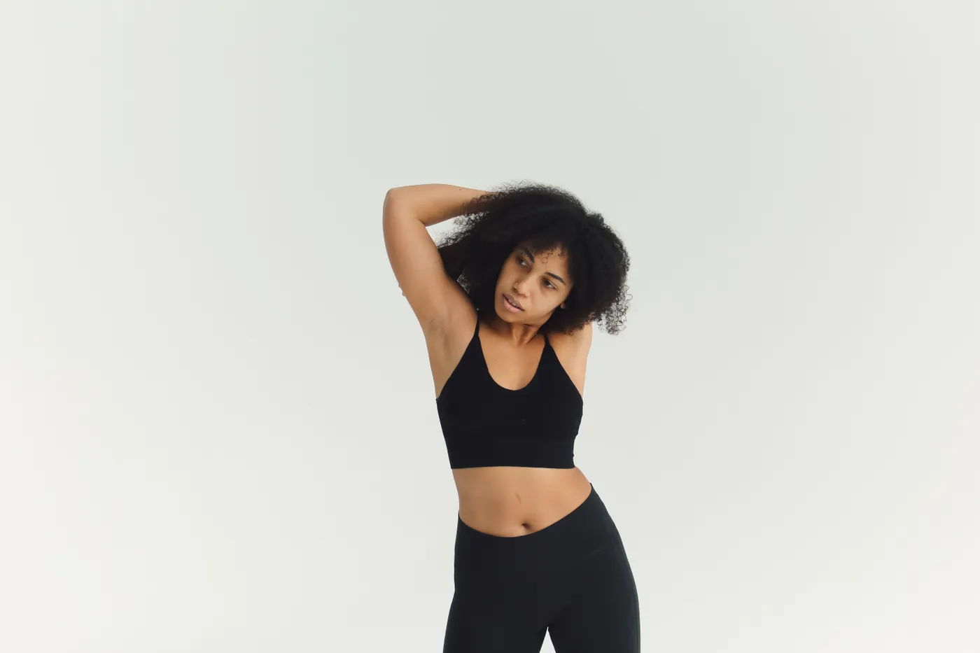 Woman practicing a controlled shoulder stretch in a bright studio