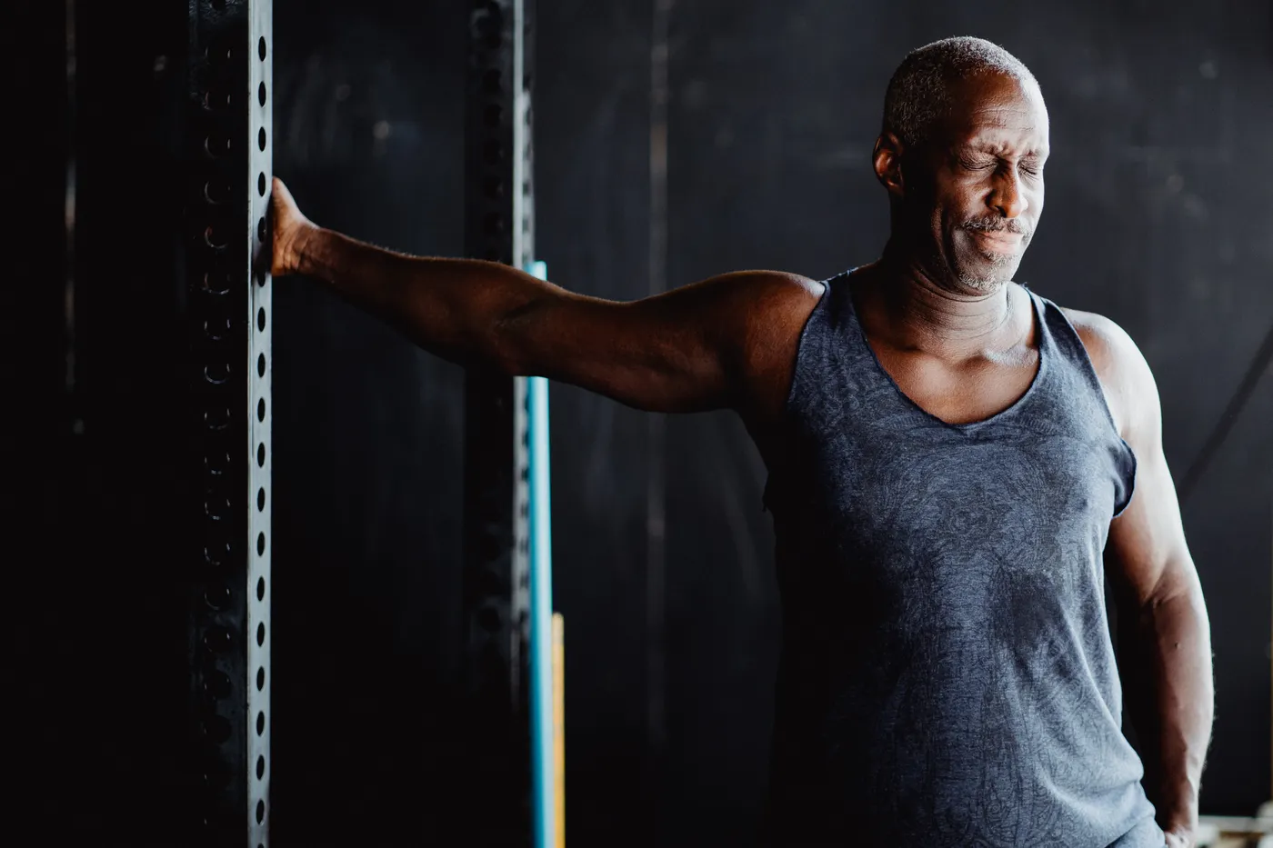 Man stretching his shoulder and upper arm in a gym