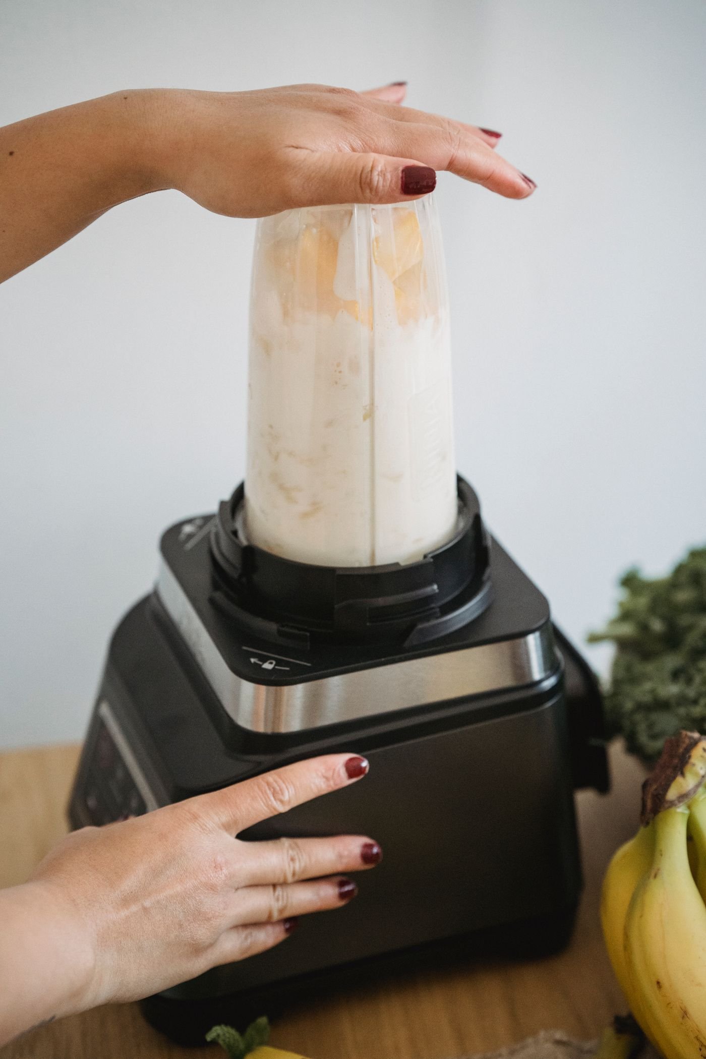 Person blending a smoothie with fruit and greens