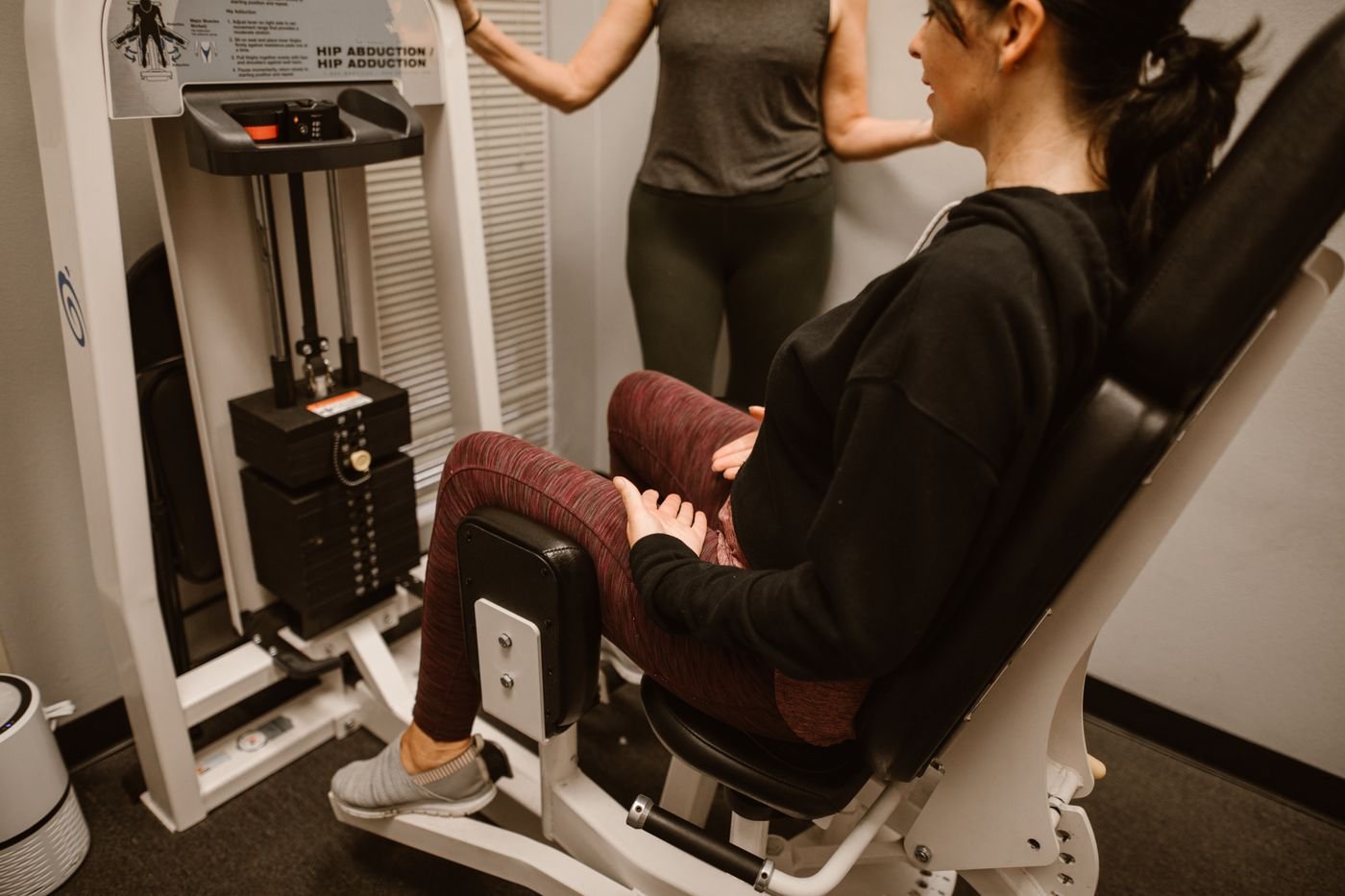 Woman training her hips on a seated hip-abductor machine