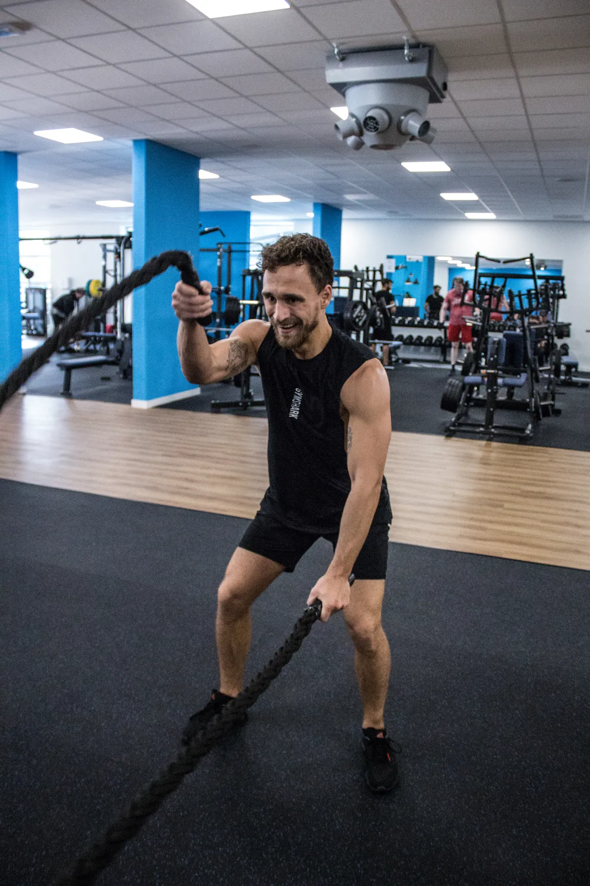 Man training with battle ropes in an indoor fitness facility