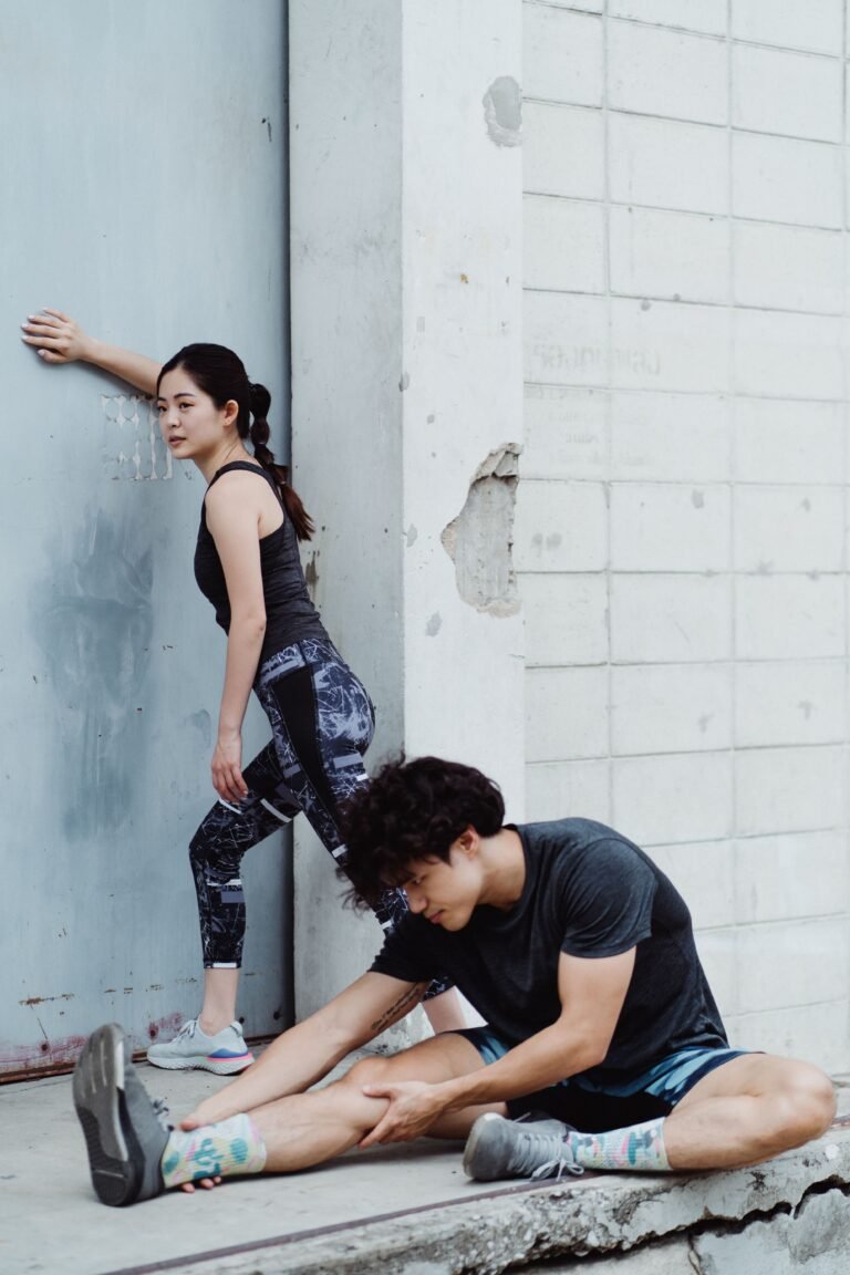 Two athletes stretching outdoors before a workout