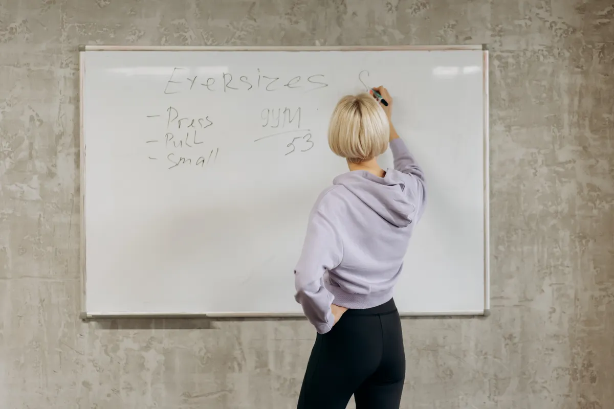 Fitness coach writing a workout plan on a gym whiteboard