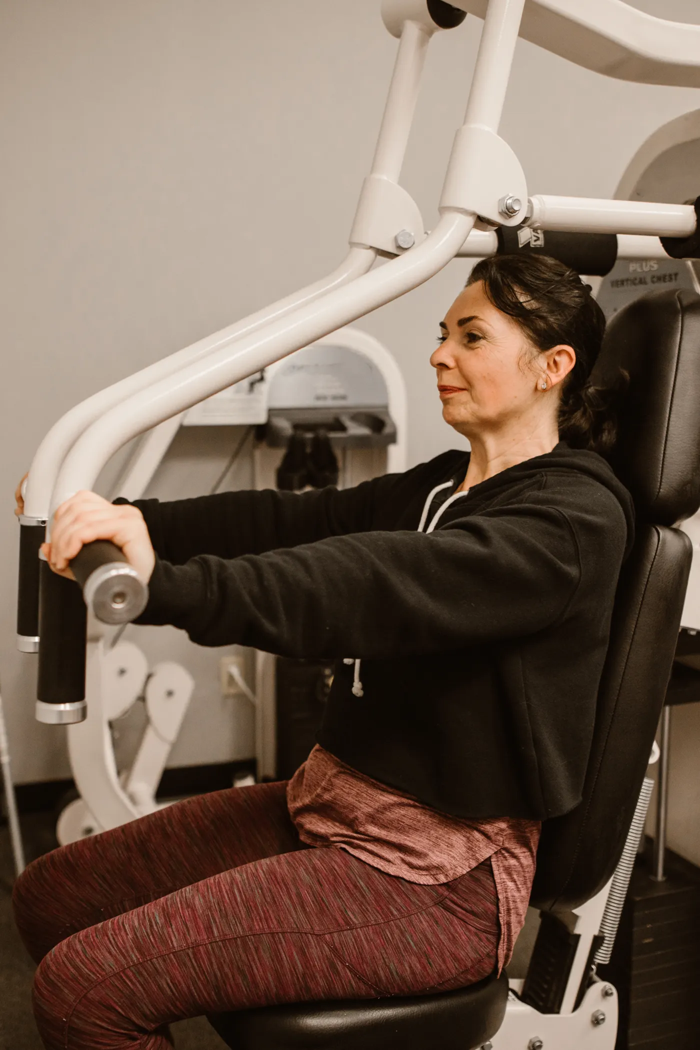 Middle-aged woman using a chest press machine at a fitness center