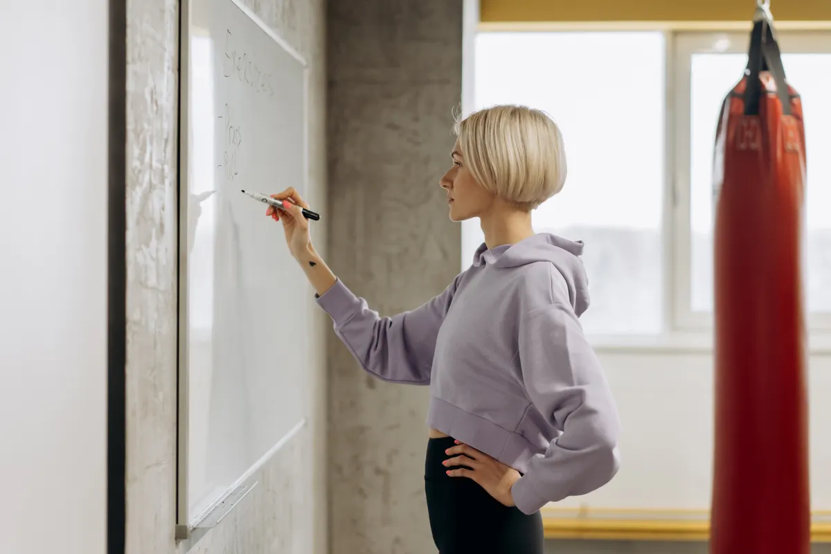Fitness trainer writing a workout plan on a gym whiteboard