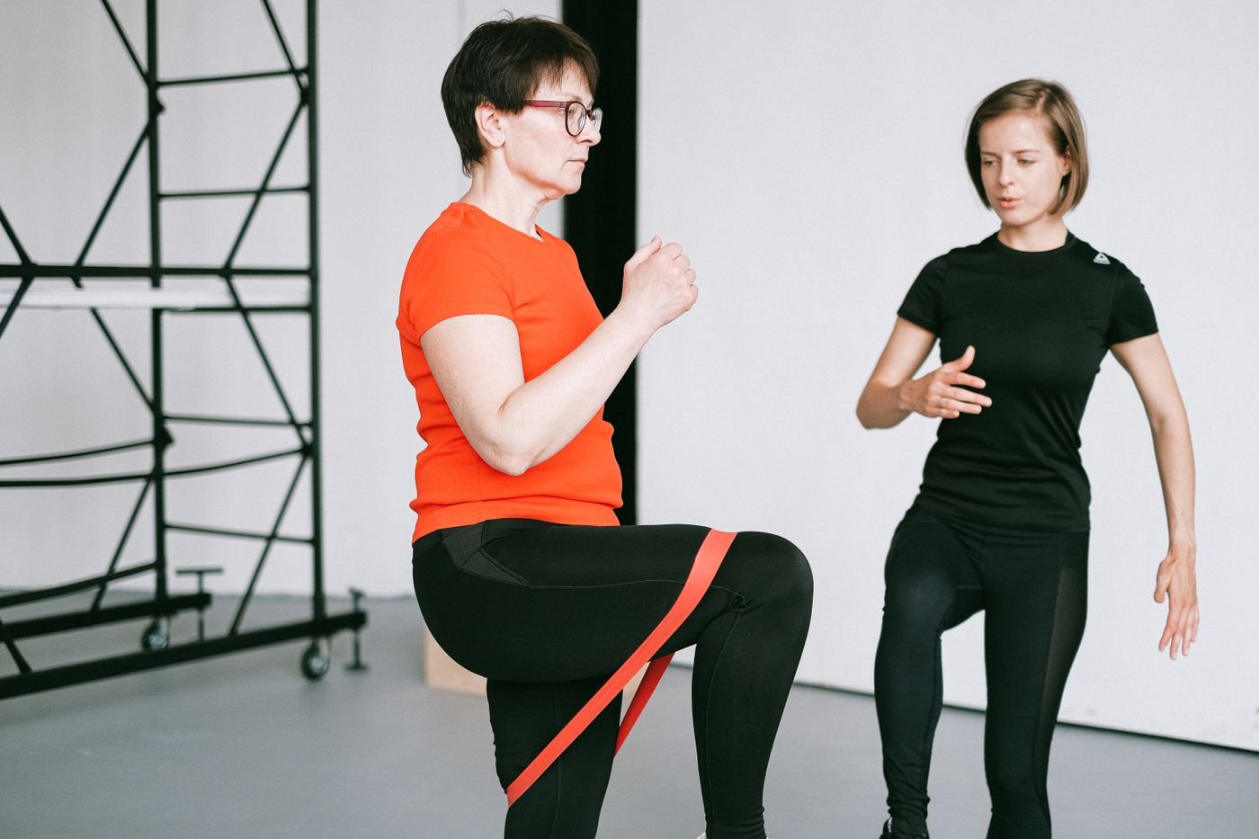 Trainer guiding a woman through a resistance-band exercise
