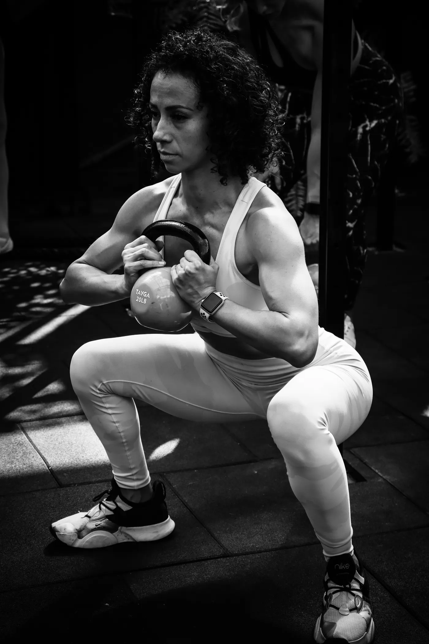 Woman performing a kettlebell squat in a gym
