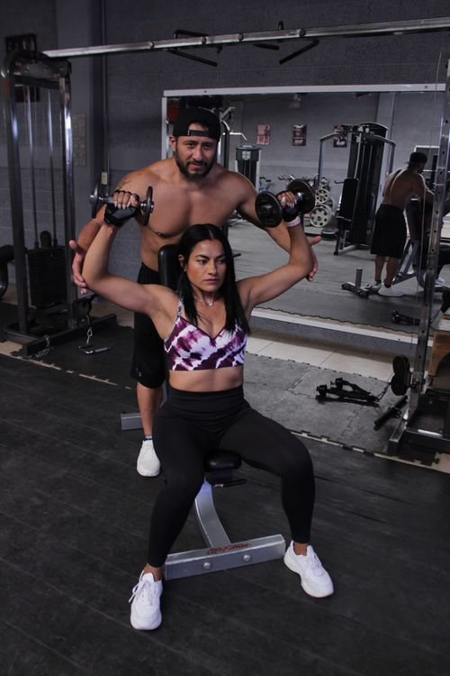 Trainer spotting a lifter during a dumbbell shoulder press