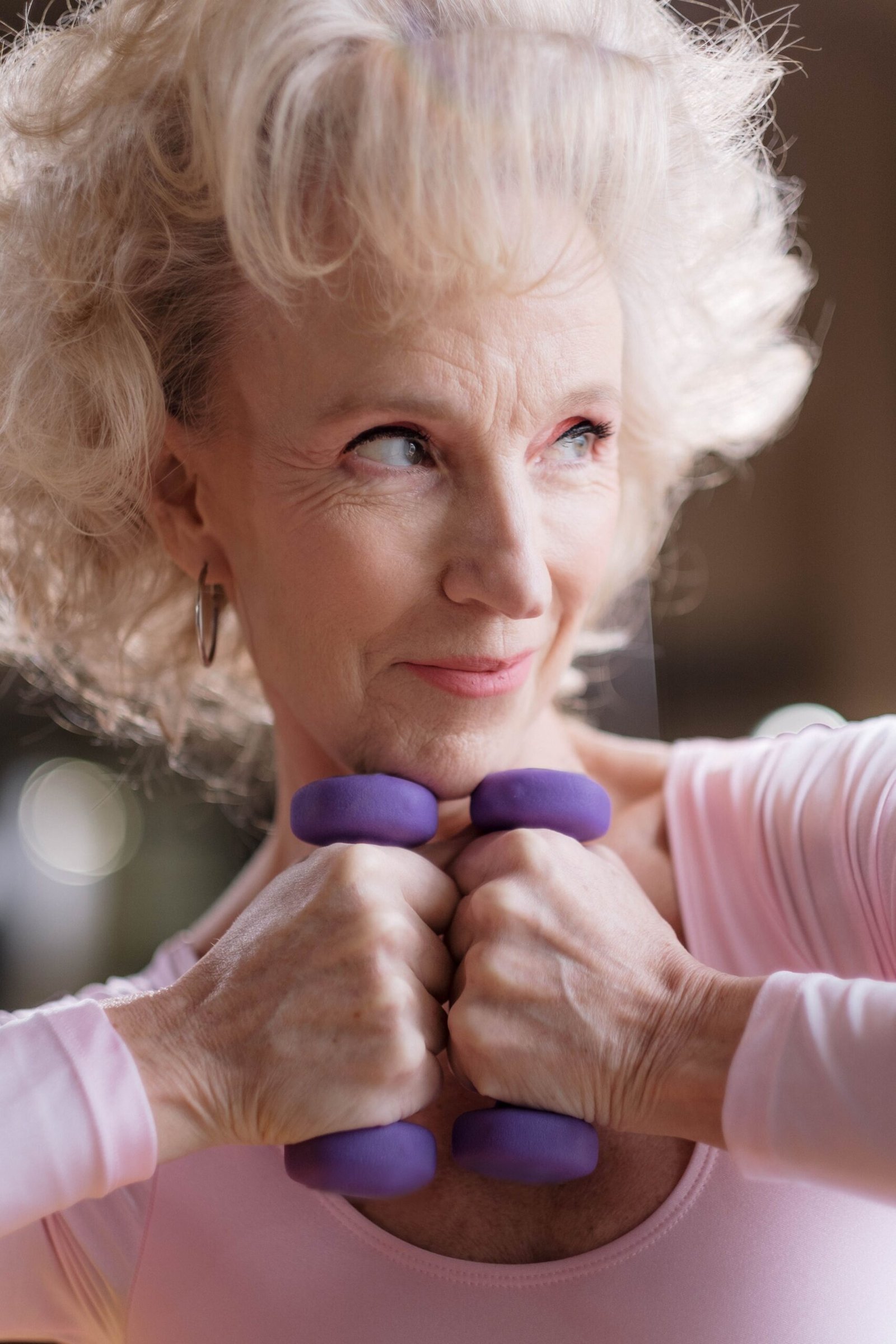Older woman training with purple dumbbells indoors