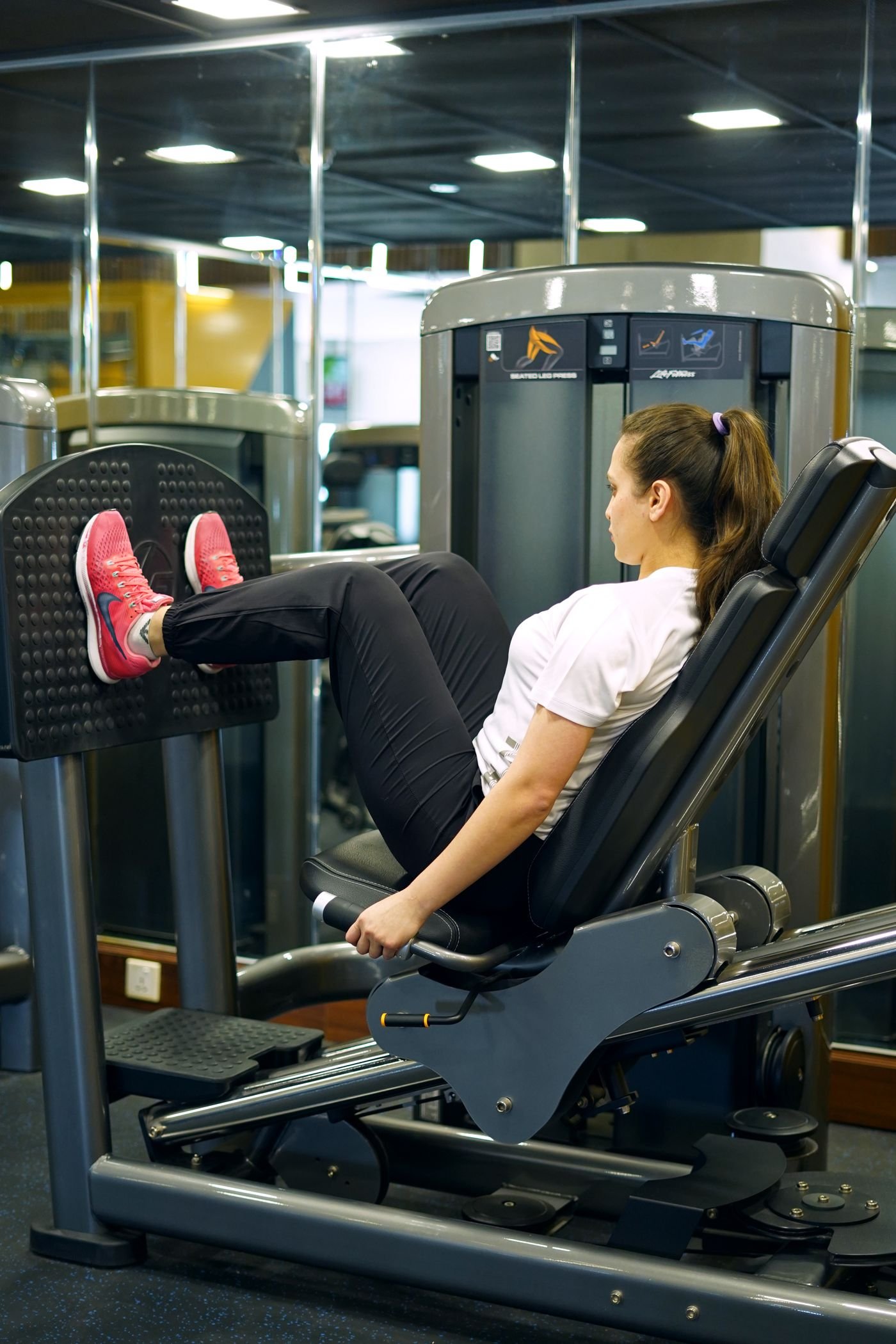 Woman training her legs on a gym leg-press machine