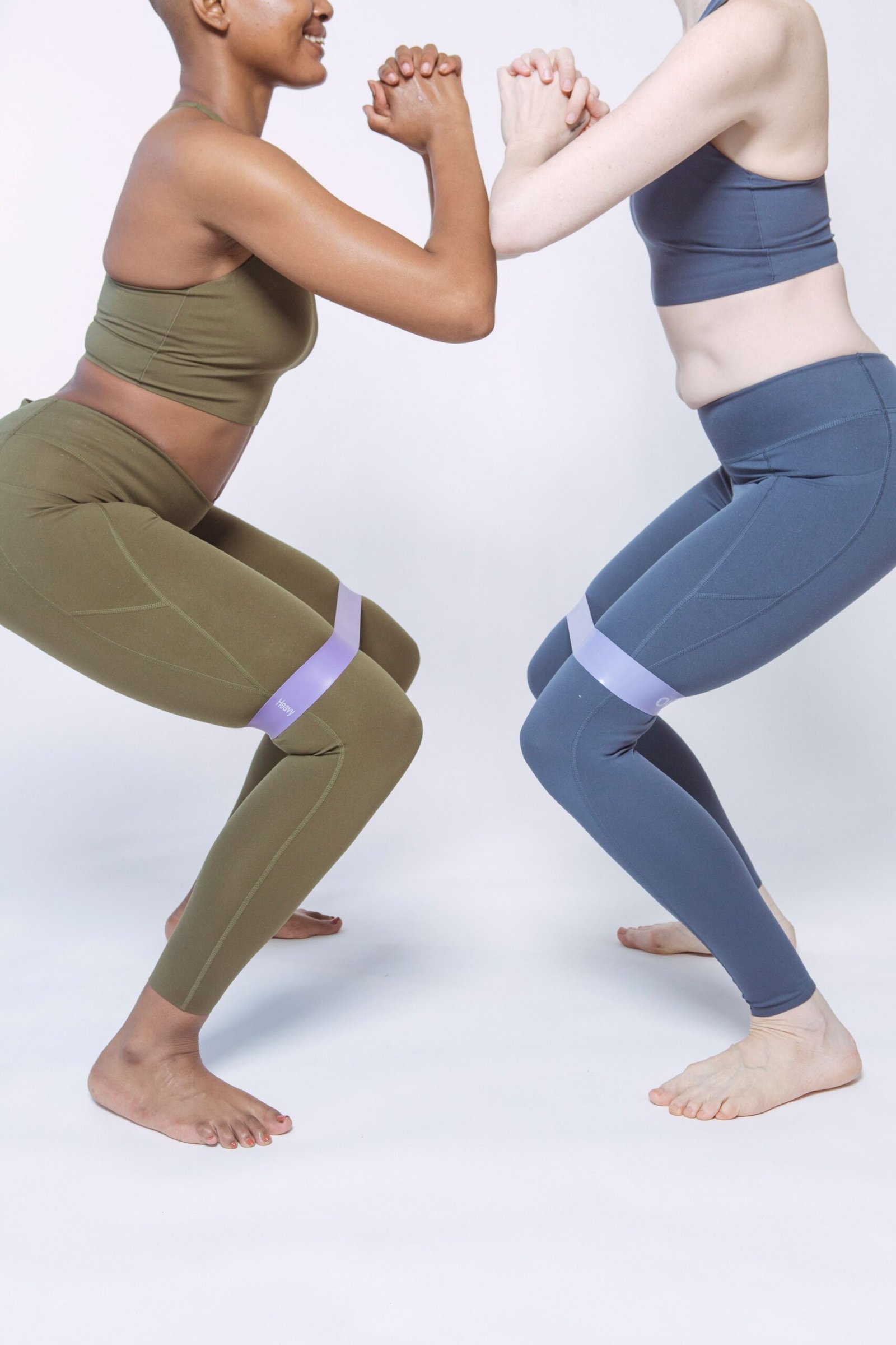 Two women performing band-resisted squats in a studio