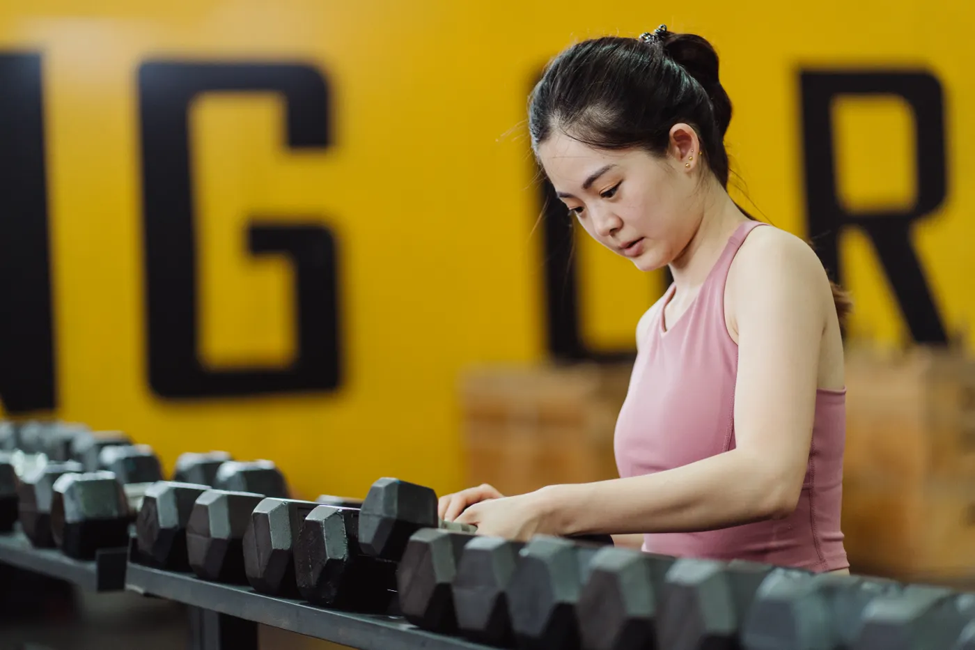 Woman selecting dumbbells for a gym workout