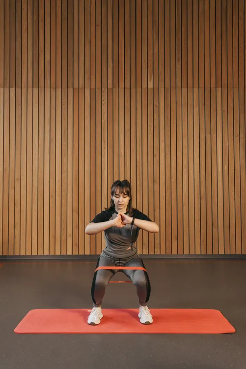 Woman using an elastic band for a lower-body exercise in a gym