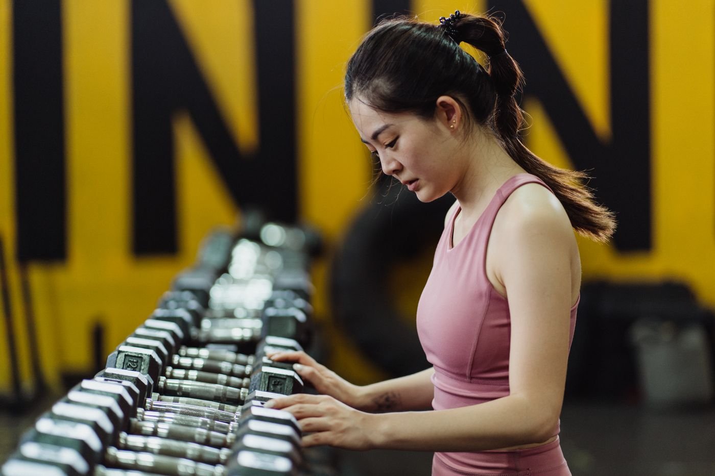 Woman selecting dumbbells from a gym rack