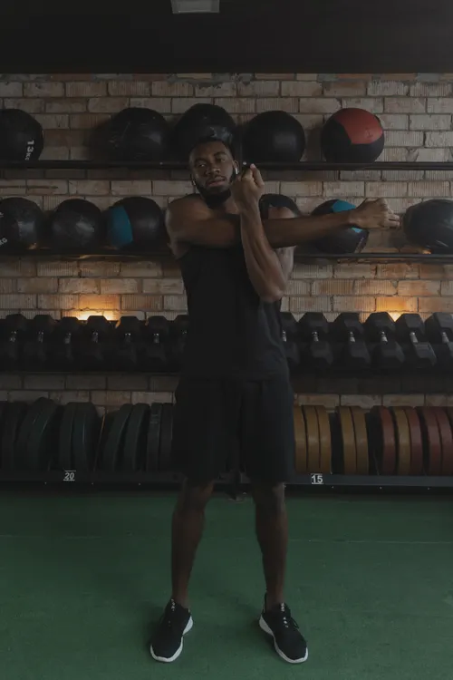 Athlete stretching his shoulder in a weight-training gym