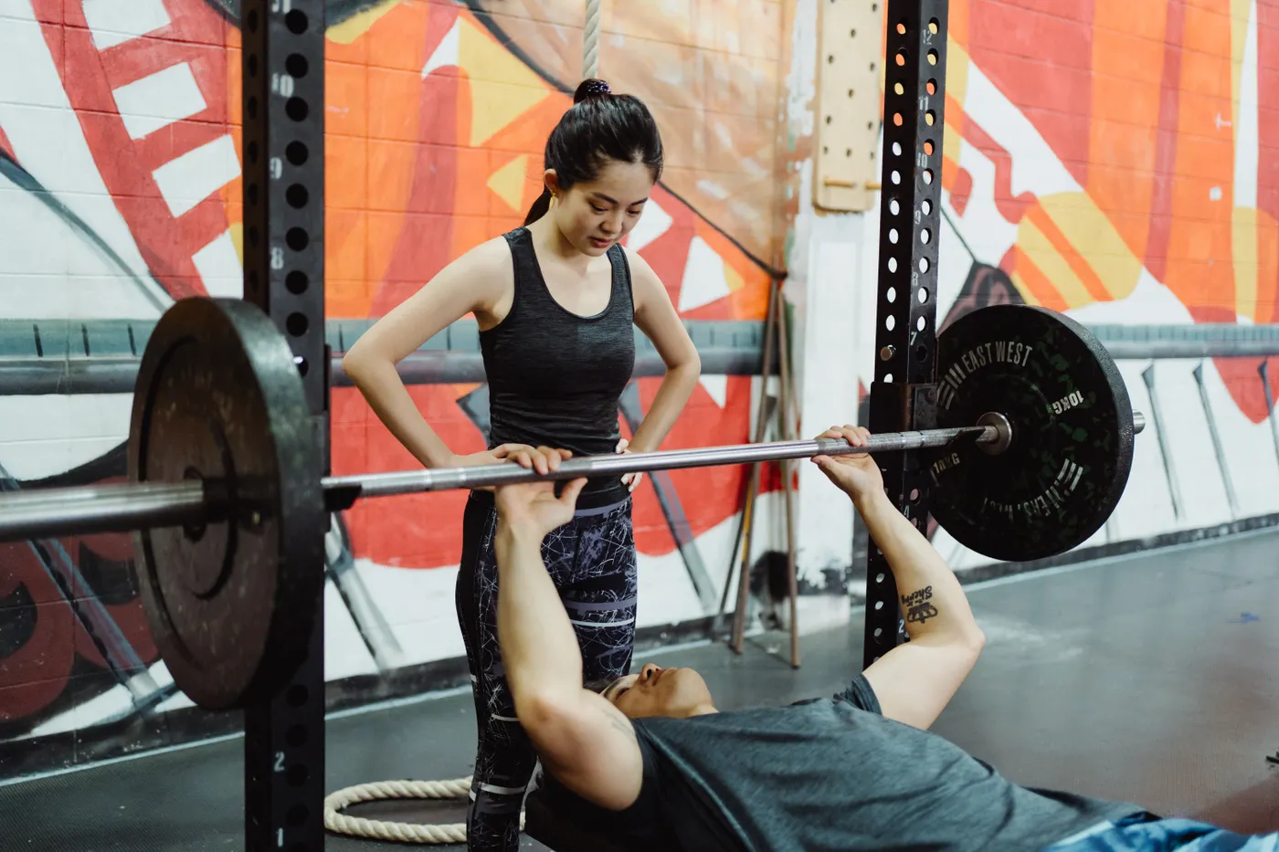 Man and woman training around a bench-press station