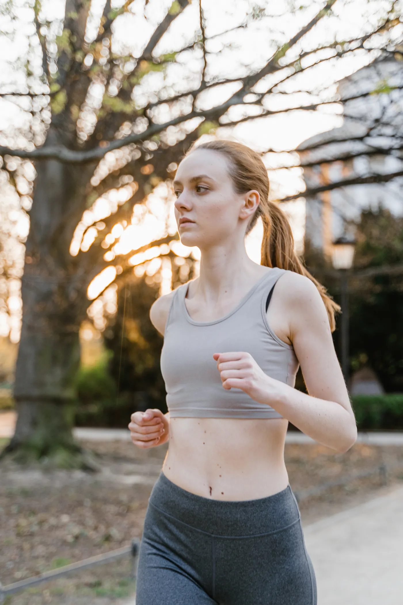 Woman jogging through a park at sunset, illustrating sustainable aerobic exercise