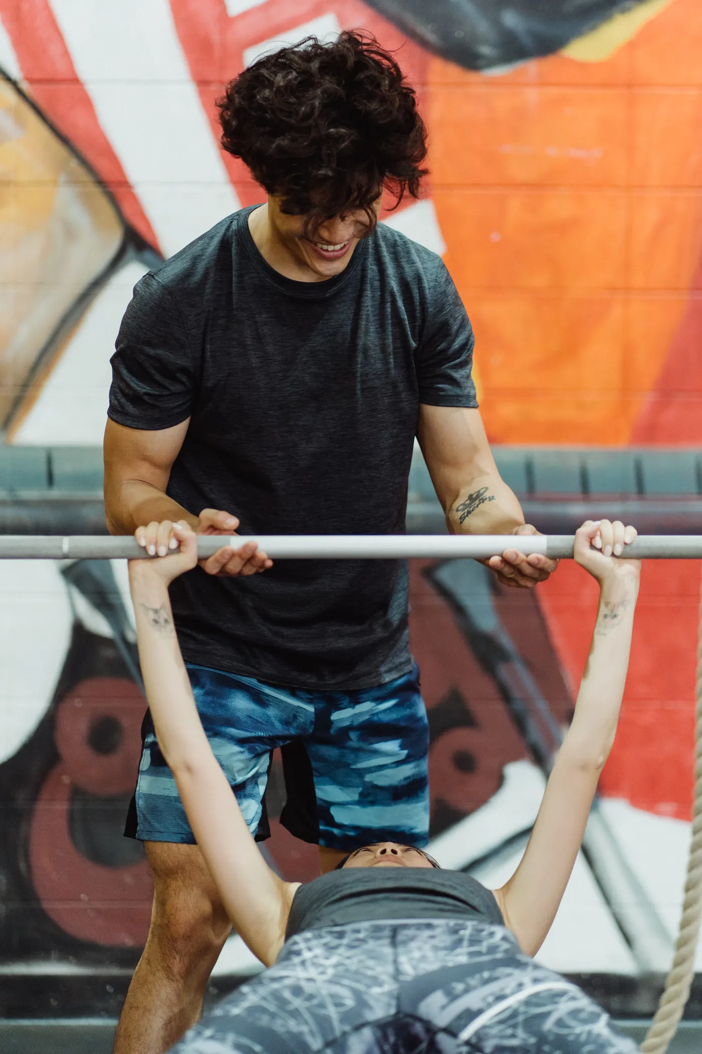 Woman performing a supervised barbell bench press in a gym