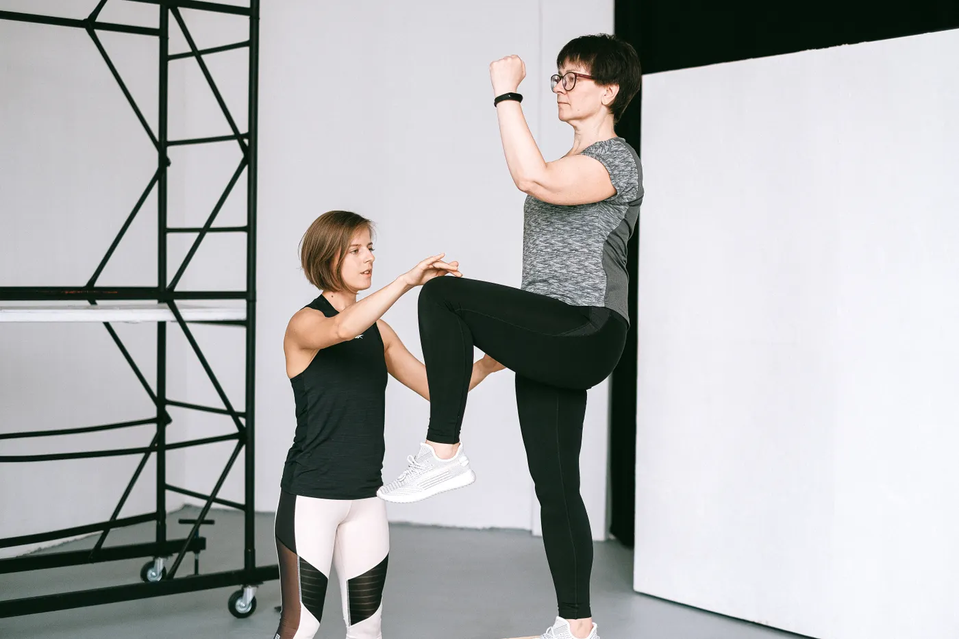 Older woman practicing an exercise with guidance from a coach