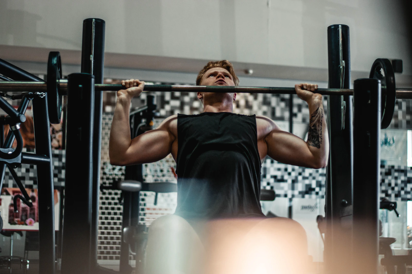 Lifter performing a barbell bench press in a weight-training gym