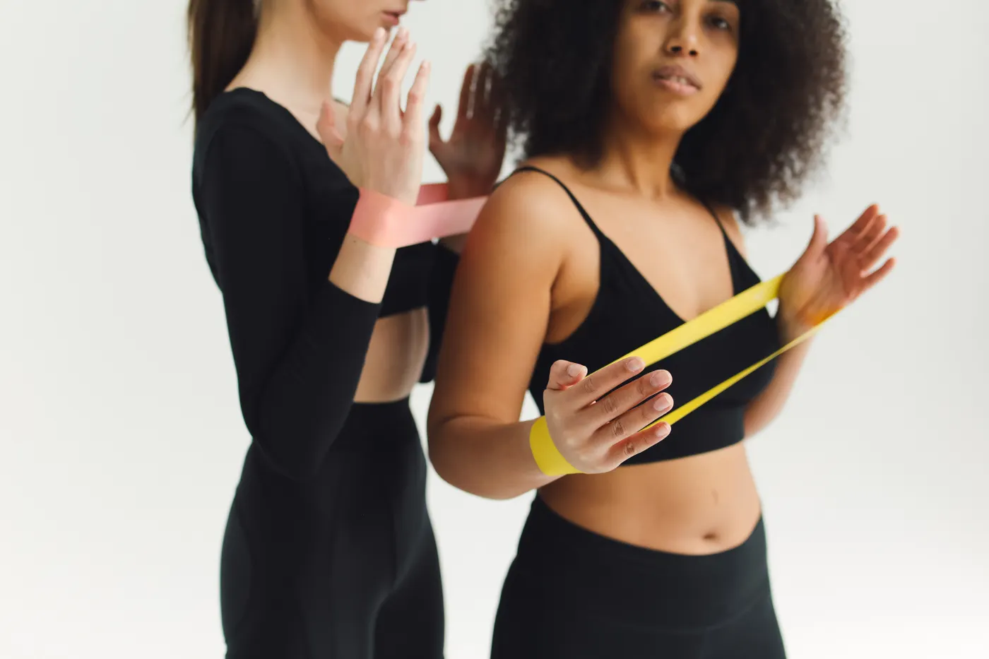 Two women exercising with resistance bands in a fitness studio