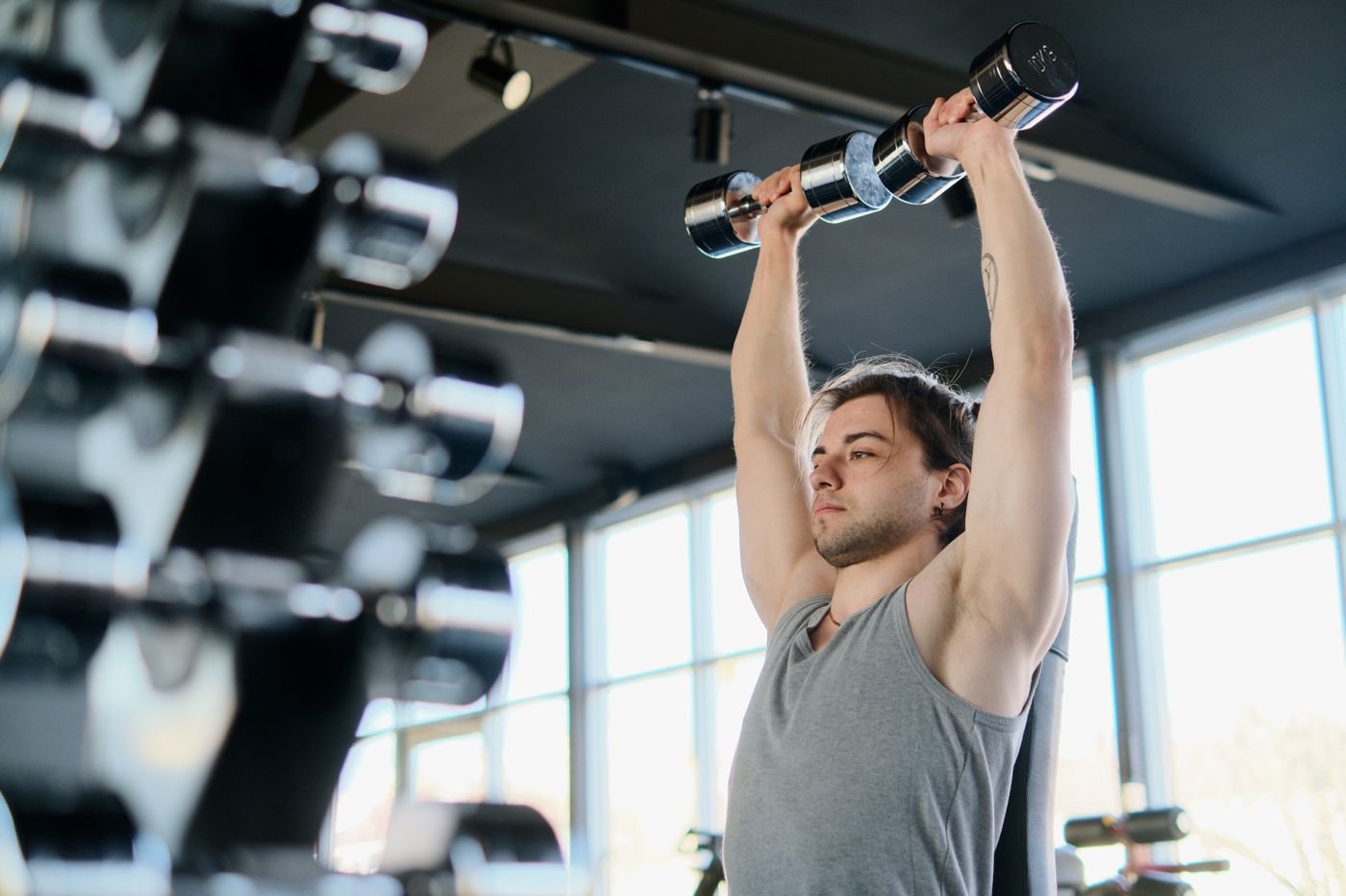 Man pressing dumbbells overhead during a shoulder workout