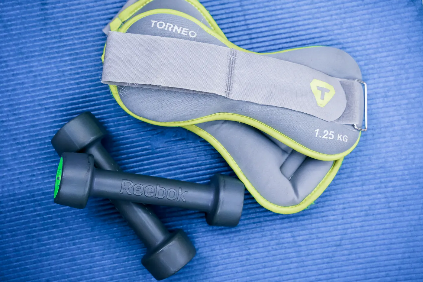 Light dumbbells and ankle weights on an exercise mat