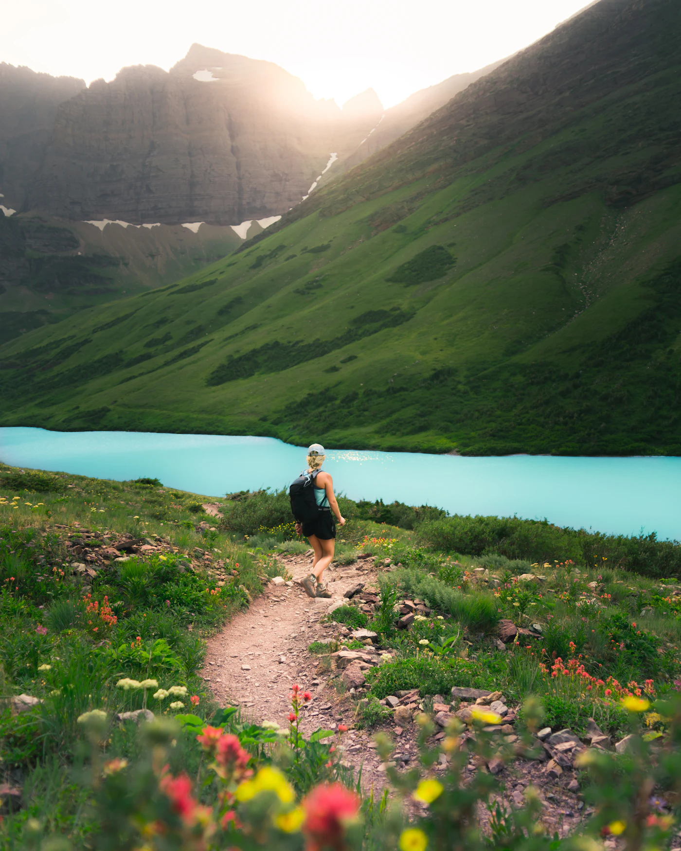 Backpacker walking along a mountain lakeside path