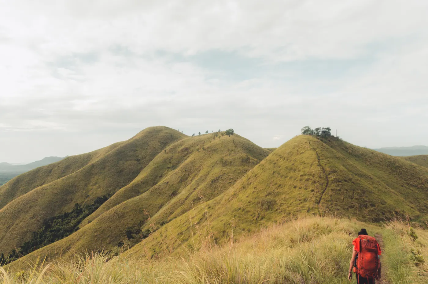 Backpacker walking along a grassy mountain ridge