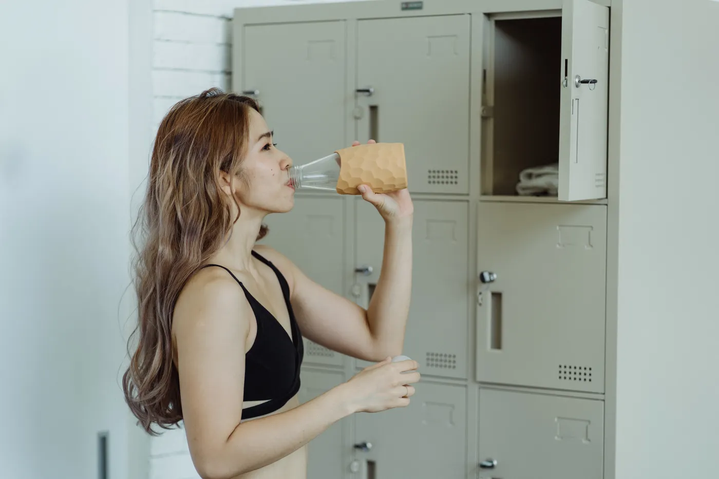 Woman drinking water after training in a locker room