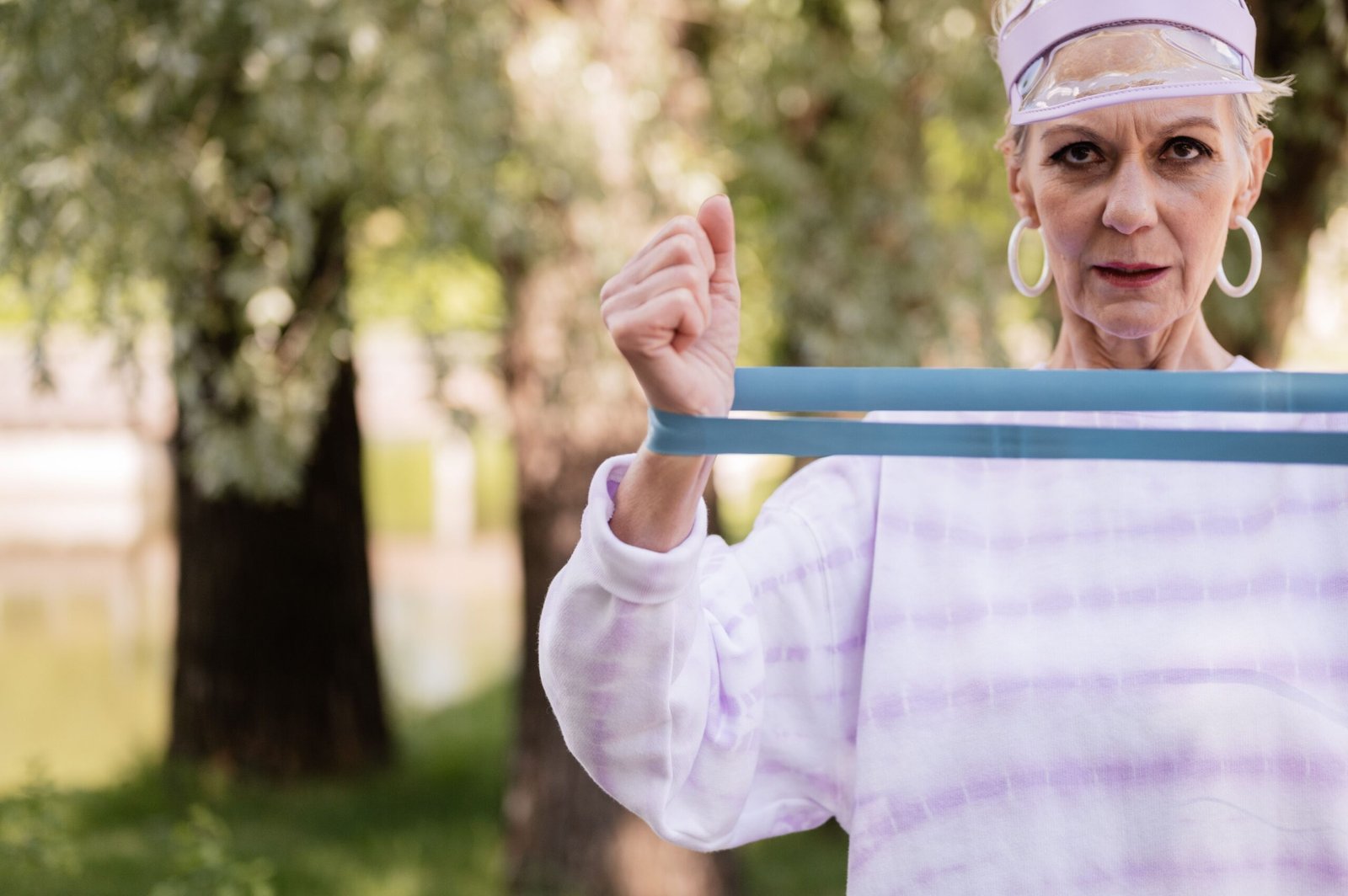 Older woman practicing resistance-band exercises in a park