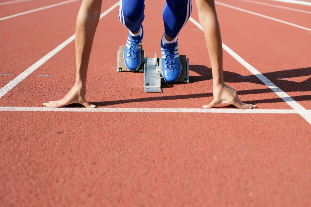 Sprinter pushing off the starting line on an outdoor athletics track