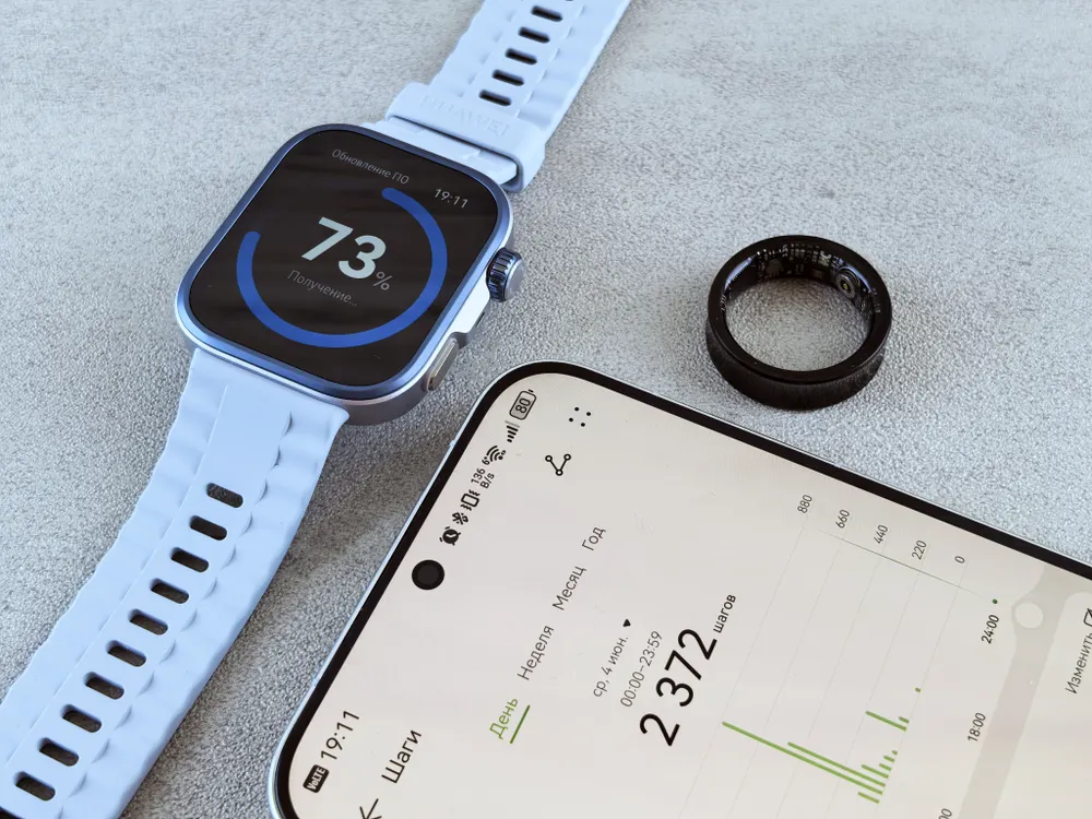 Smartwatch, fitness tracking phone and health ring on a gray surface