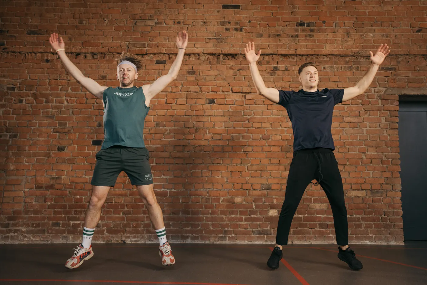 Two people doing jumping jacks in a gym