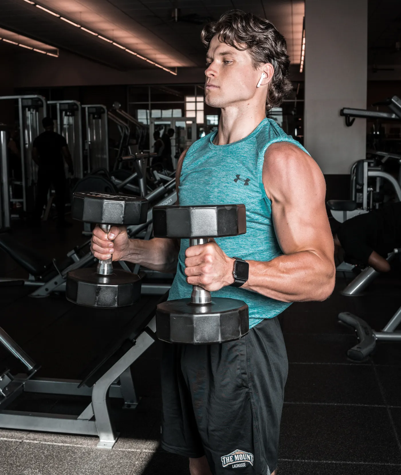 Man carrying dumbbells while standing upright in a gym
