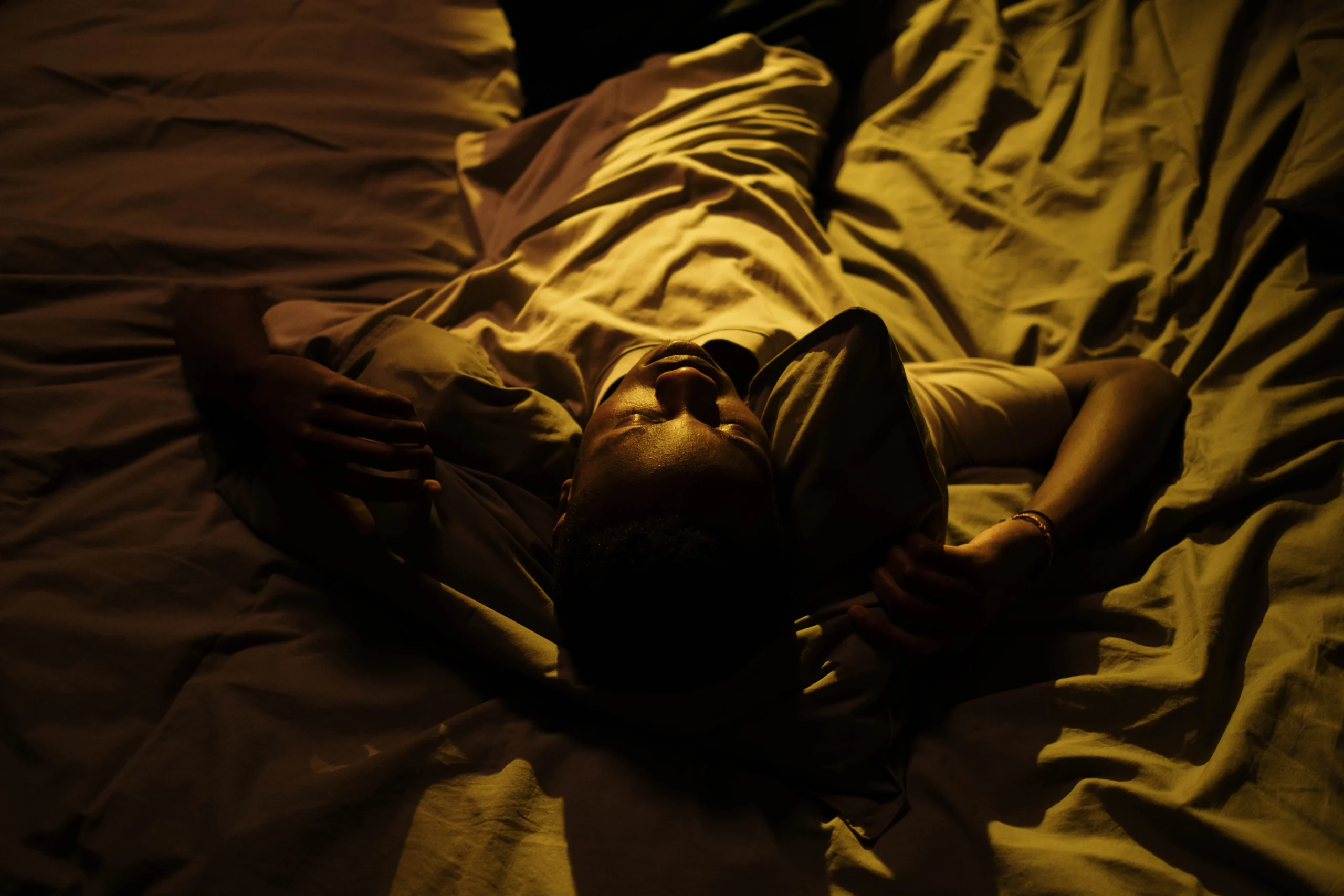 Man awake in a dark bedroom during a restless night
