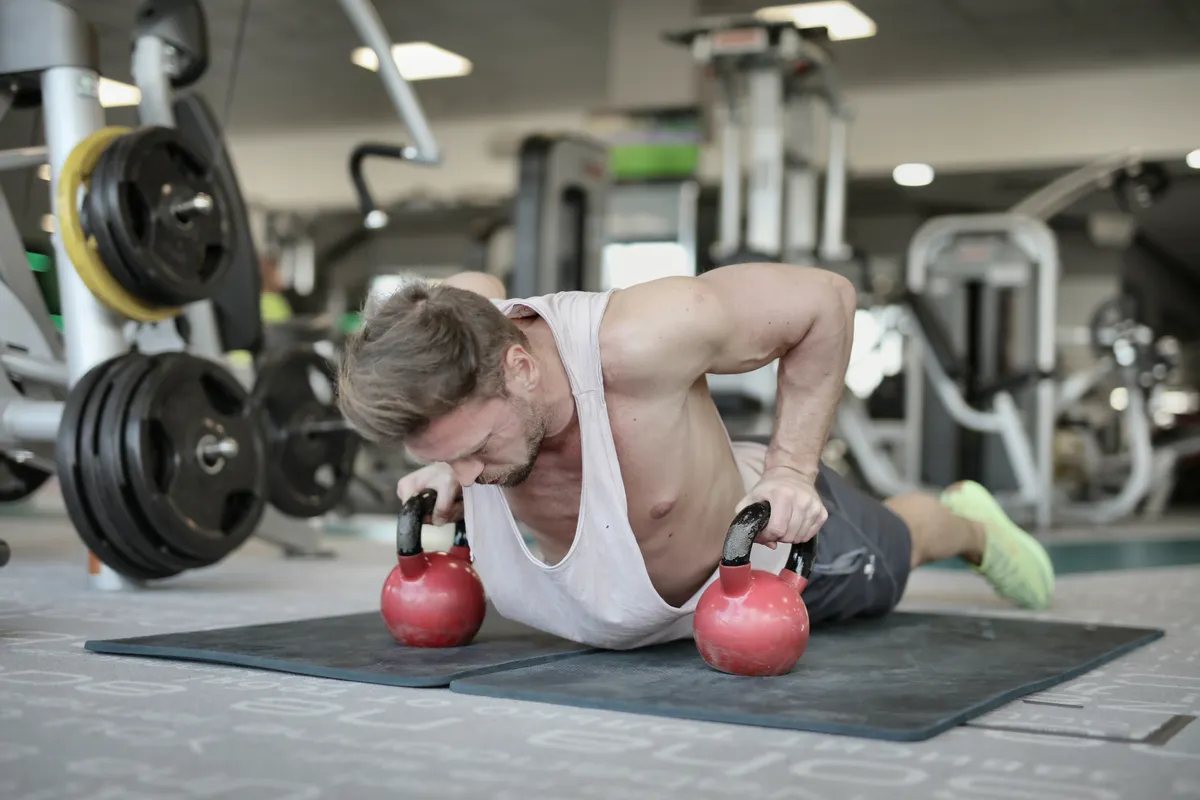 Athlete performing a push-up on kettlebells in a gym