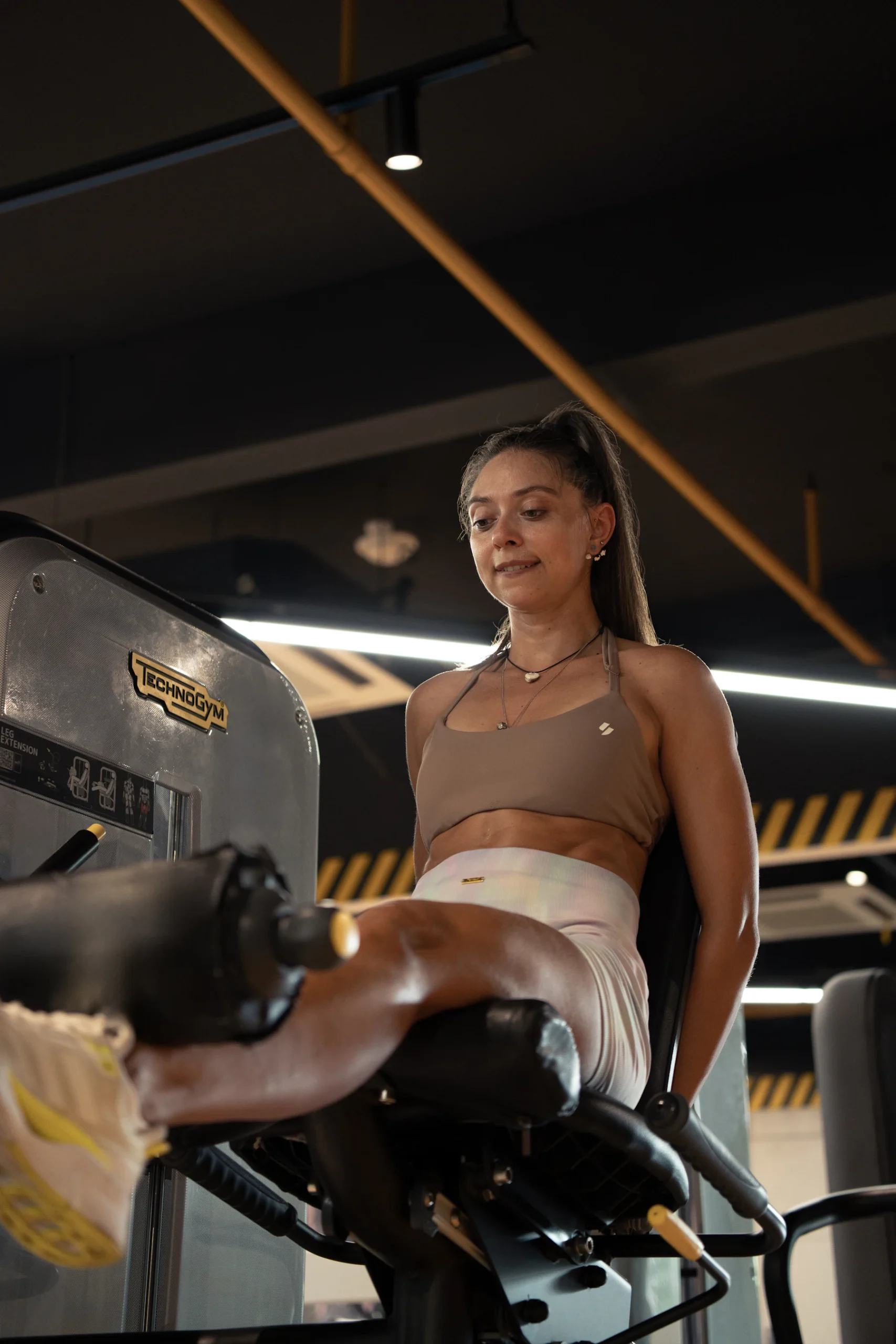 Woman performing seated leg extensions on a resistance machine in a gym