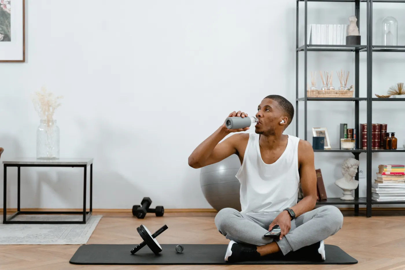 Man hydrating while resting on a mat after exercise