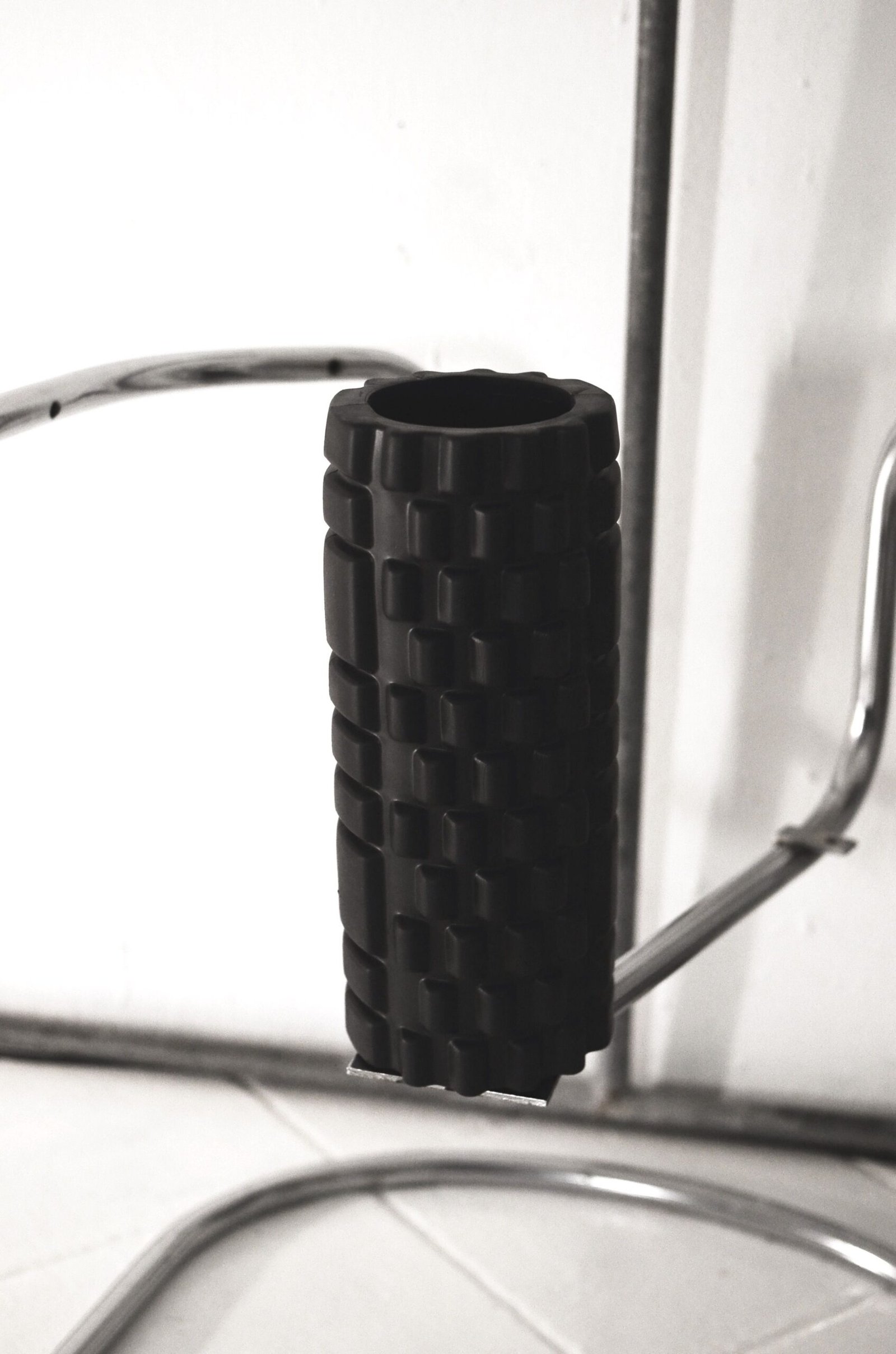 Black textured foam roller resting on gym equipment