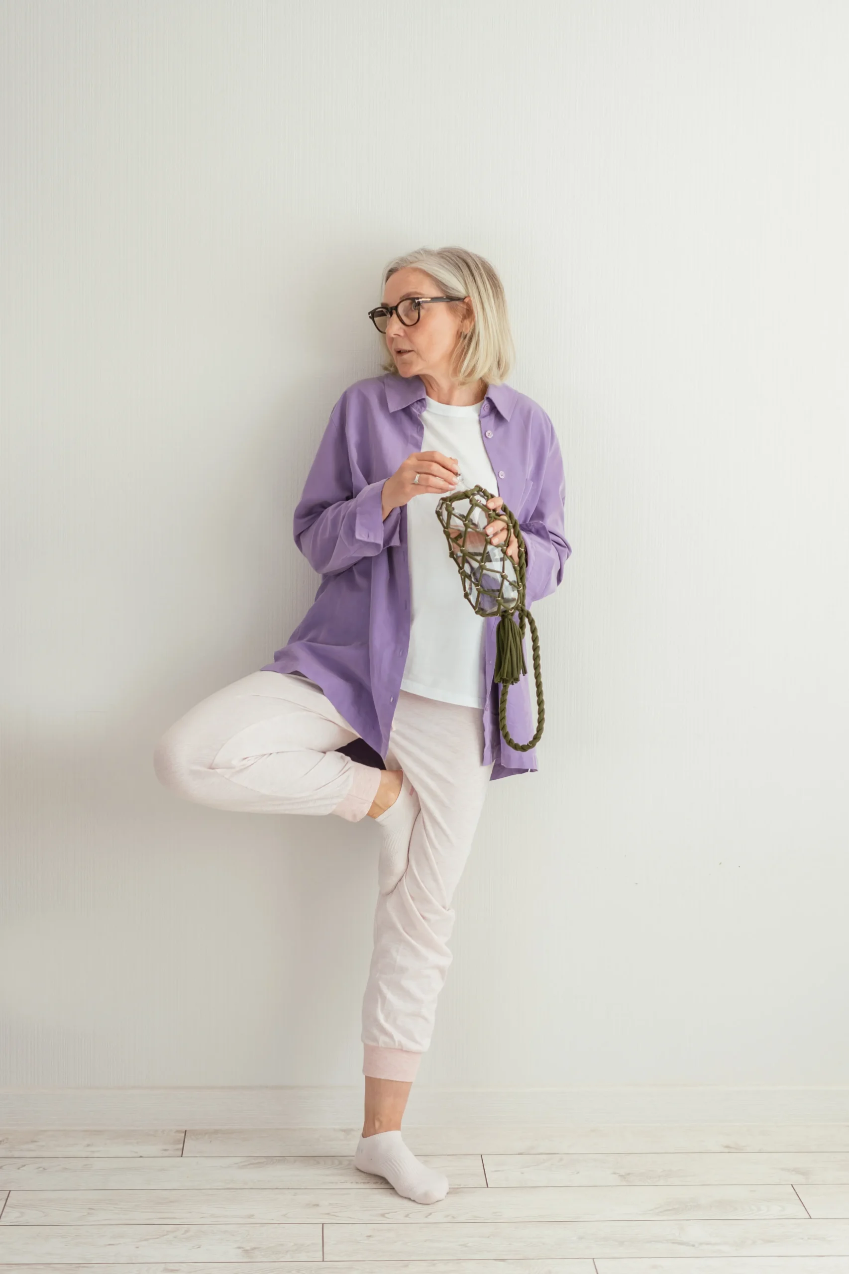 Older woman practicing a supported single-leg balance exercise indoors